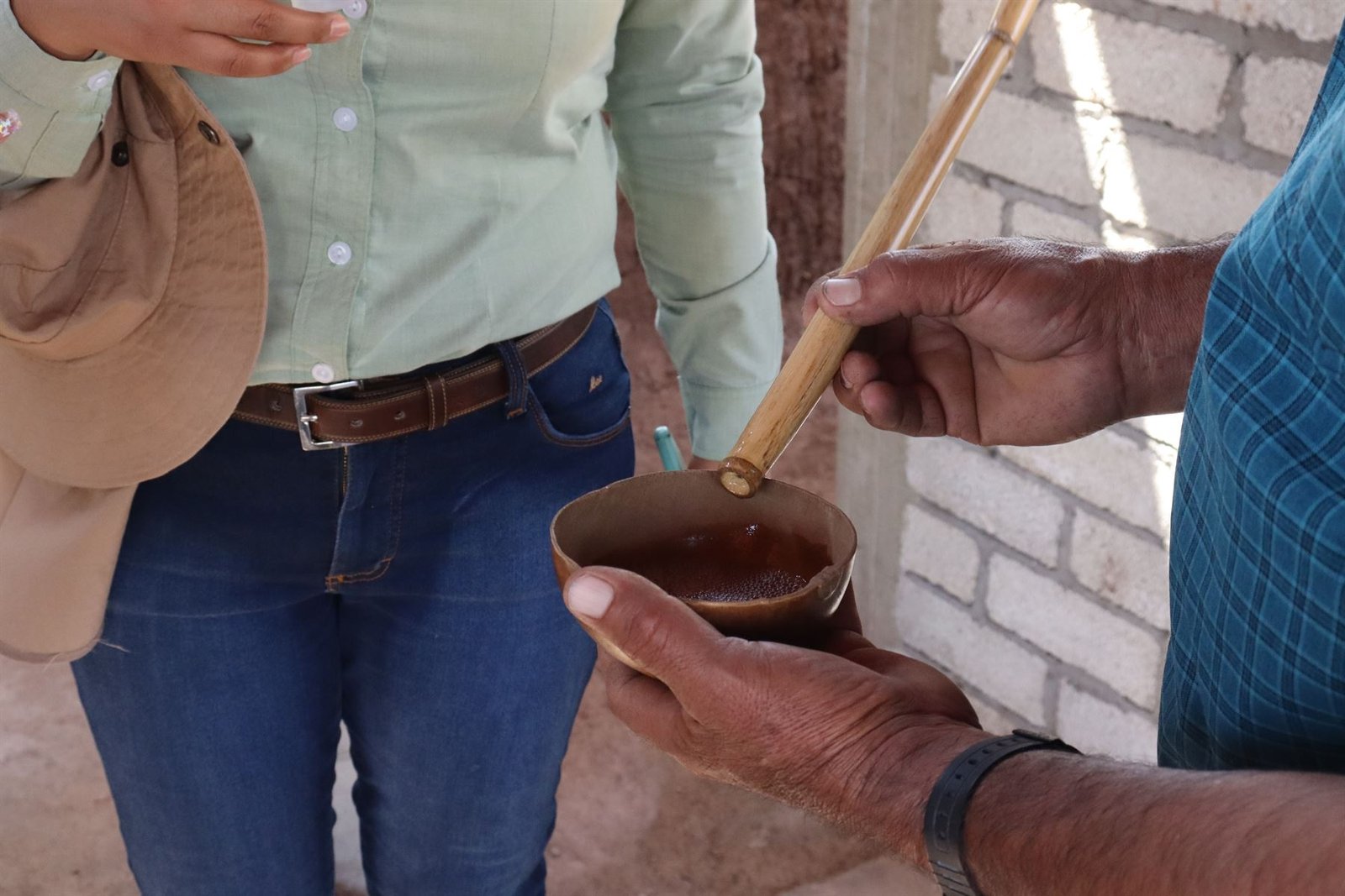 Manos sosteniendo una jícara de barro con mezcal