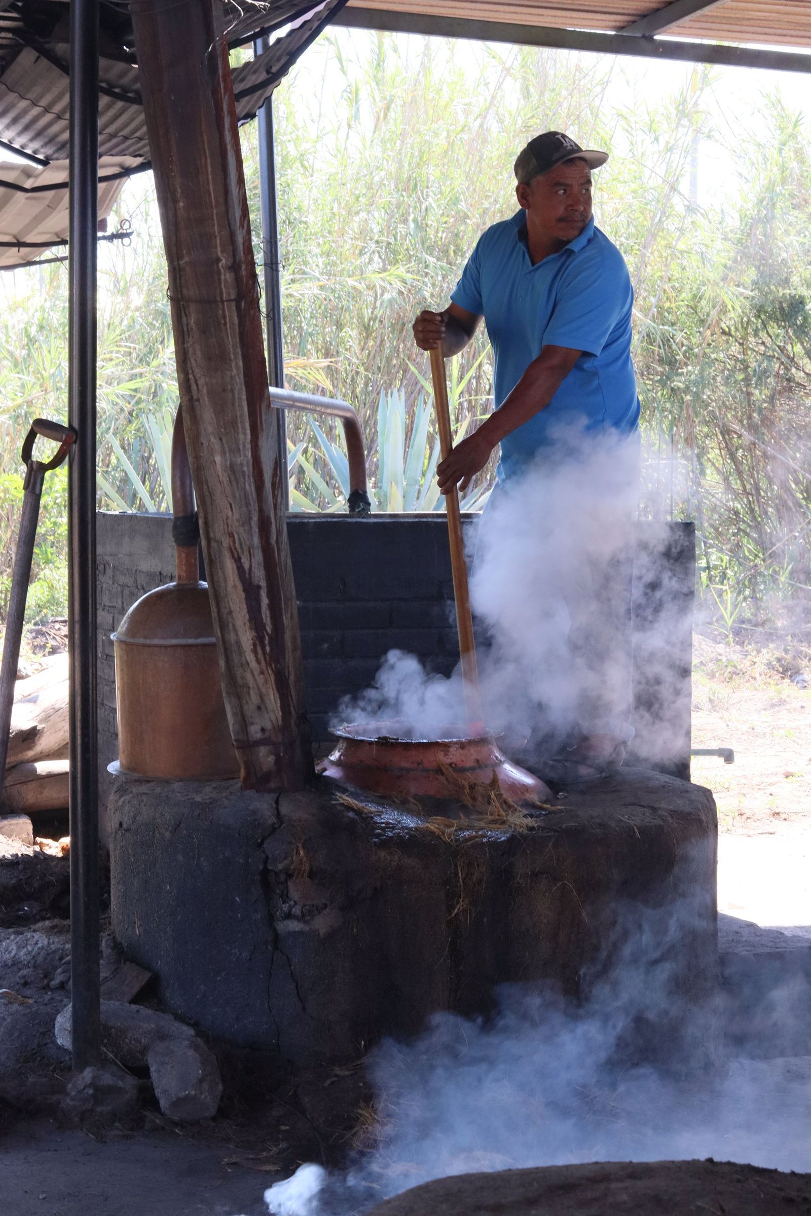 Maestro mezcalero trabajando en el alambique entre el vapor